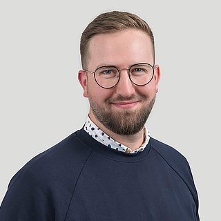 Mann in blauem Pullover mit Brille und Vollbart